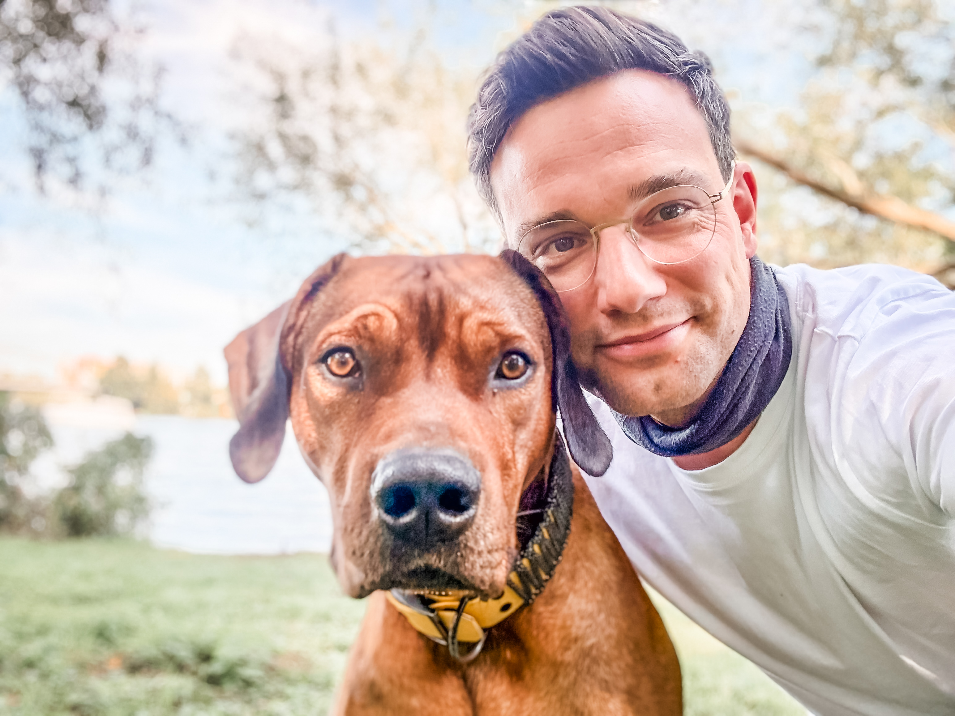 Paul Herrig zusammen mit einem braunen Hund in einer Nahaufnahme im Freien.